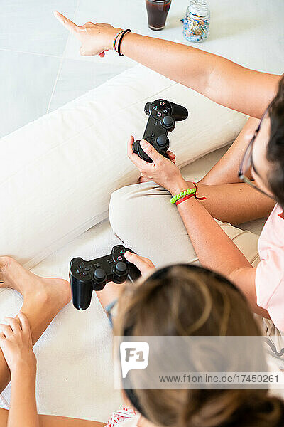 Mother and daughter playing video games together sitting on floor.