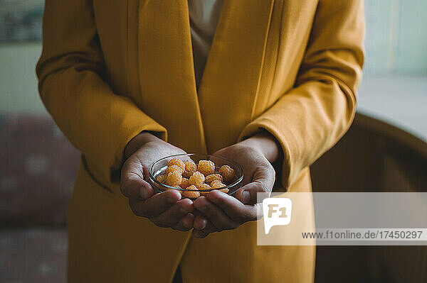 Yellow raspberries in glass plate in hands