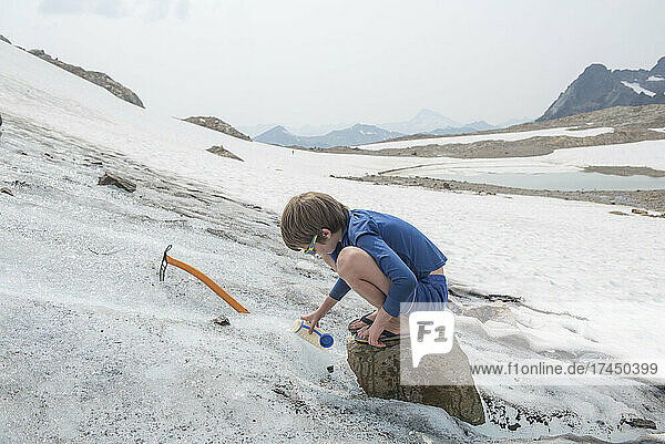 Boy collects water from a glacier near Glacier Peak  WA.