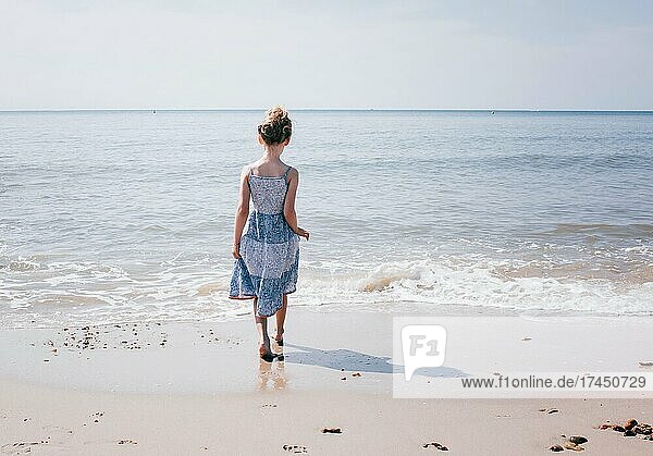 young girl at the beach walking towards the water