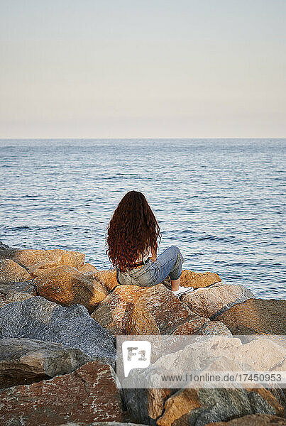 Young redhead woman on her back looks to the sea