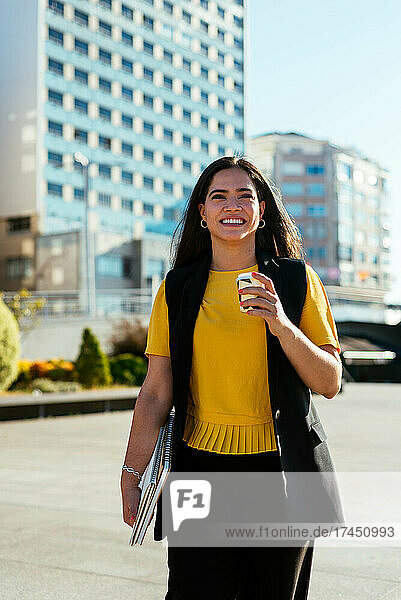 Young business woman walking on the street and holding a coffee