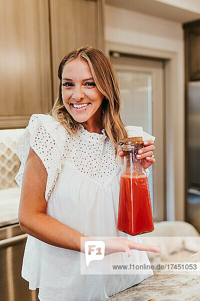 Smiling woman shows off her freshly made carafe of homemade juce