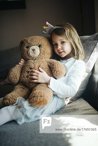 Happy little girl hugging a teddy bear at home.