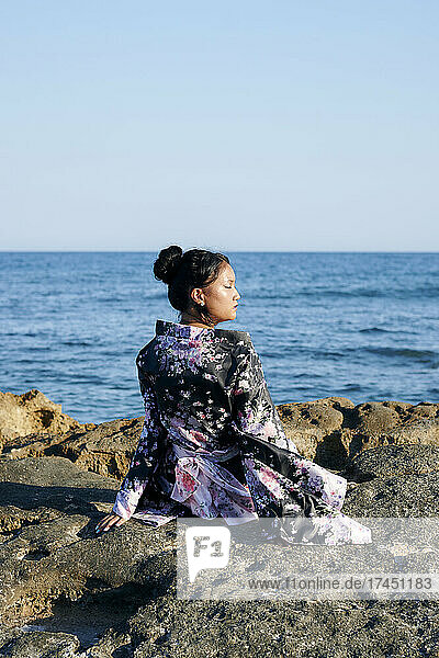 Young Asian woman dressed as a geisha with the sea in the background