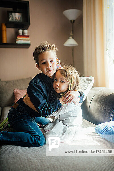 Brother and sister hugging at home.