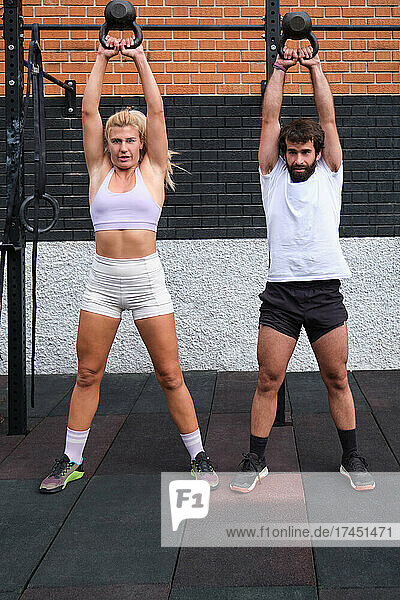 Young man and woman lifting kettlebell. Crossfit exercises.
