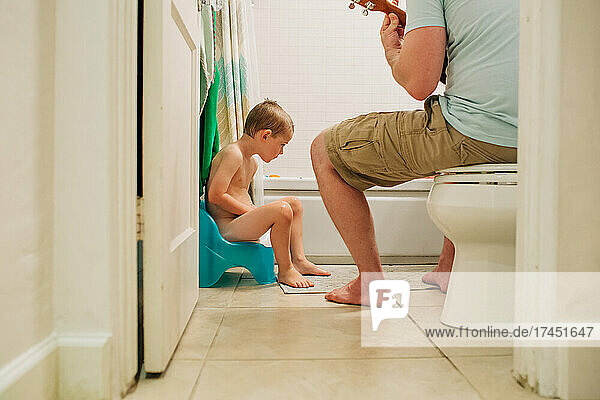 Four year old boy learning to potty train with dad helping