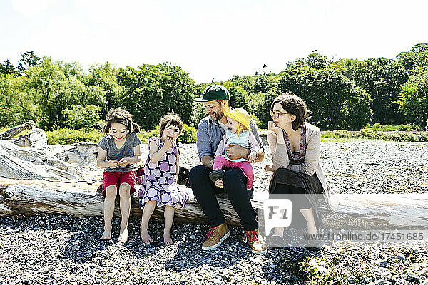 Straight on view of a family sitting on driftwood at Carkeek Park