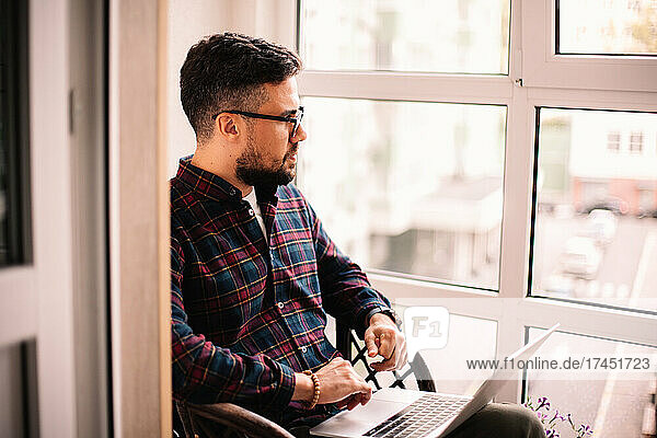 Serious thoughtful man using laptop computer at home