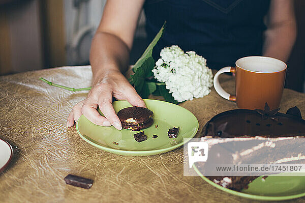 Woman takes small round chocolate cake during tea party