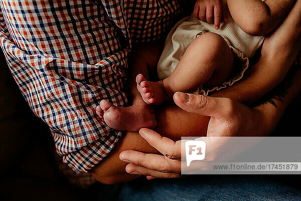 Detail shot of baby's toes and dad's hands.