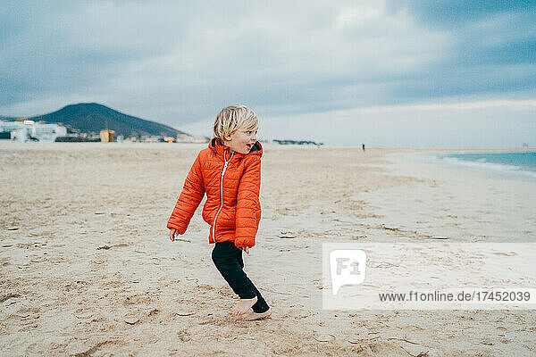 Young child running away from waves at Fuerteventura beach in winter