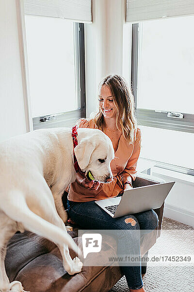 Woman plays with dog while trying to work from home