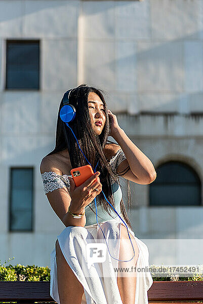 Asian woman listening to music with headphones.