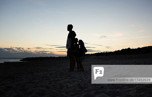 father and kids walking at the beach at sunset