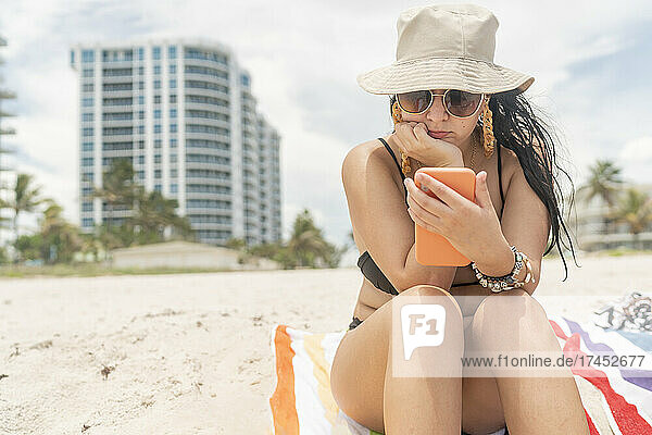 Girl on the beach checking her social networks on her cell phone