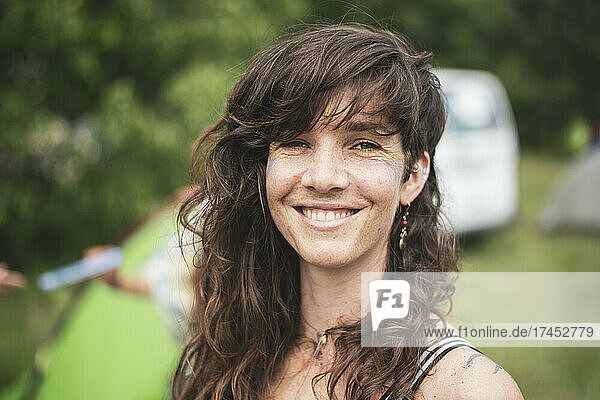 Smiling beautiful brown curly hair woman camping at festival in Poland