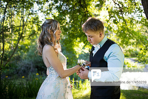 Young man attaches corsage to his dates wrist.