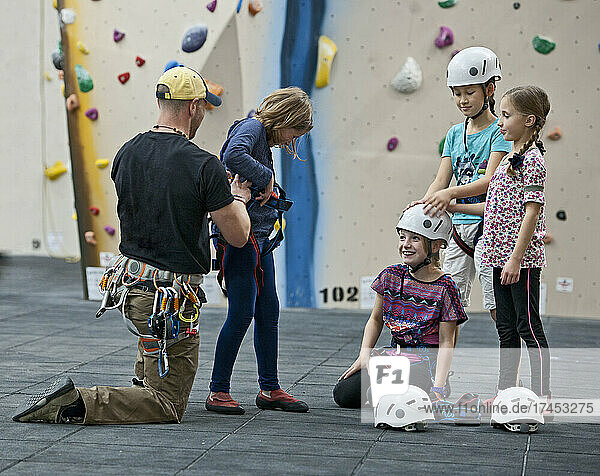 climbing coach helps girl putting climbing harness