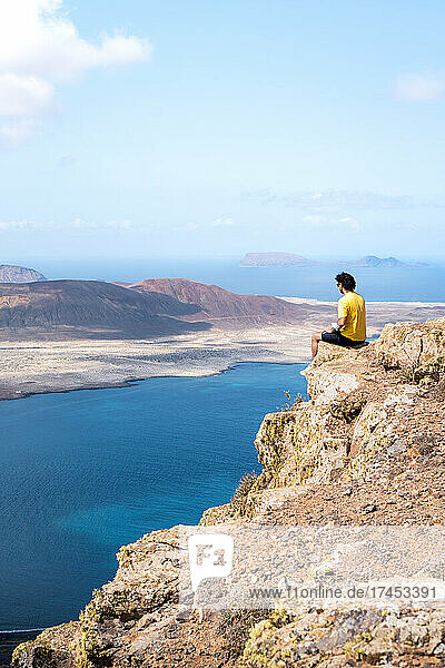 Man resting on a cliff with views of La Graciosa island  Canary island