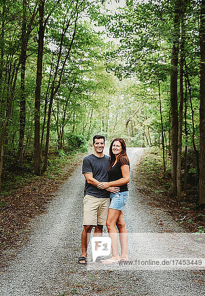 Happy couple embracing on a trail through the woods in summer.