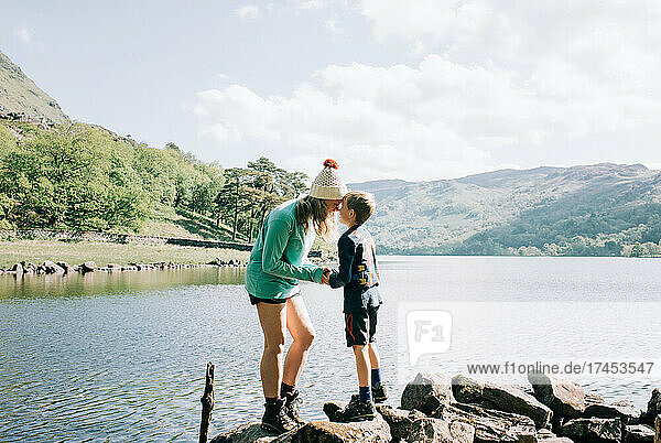 mom holding son playfully whilst hiking by a lake on vacation