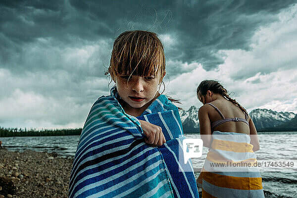 Young girls wrapped in towels near a mountain lake