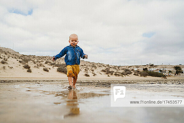Cute Boy walking at Fuerteventura dune beach on overcast day