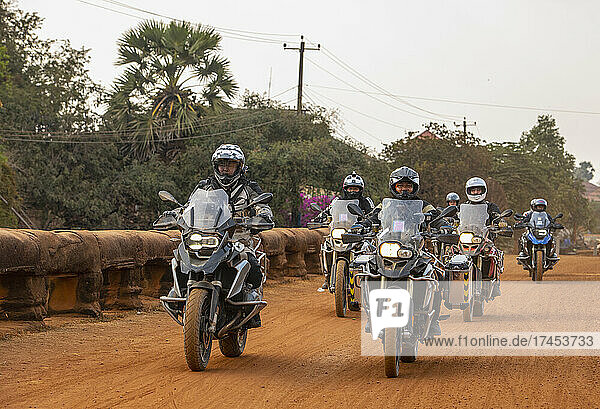 Group of men riding their adventure motorbike on dirt road in Cambodia