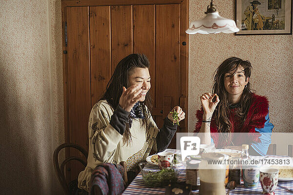 queer female couple in colourful clothes eat breakfast Czech cottage