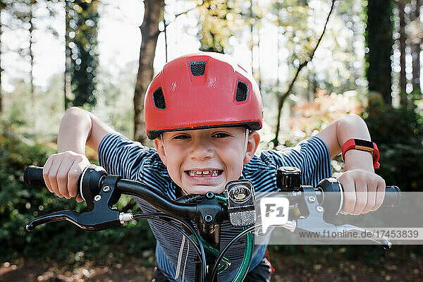 portrait of boy leaning on his bike smiling in the forest