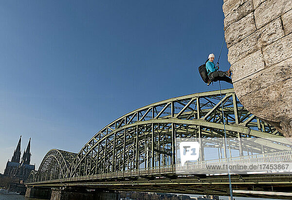 climber descending on Hohenzollern bridge in the city of Cologne