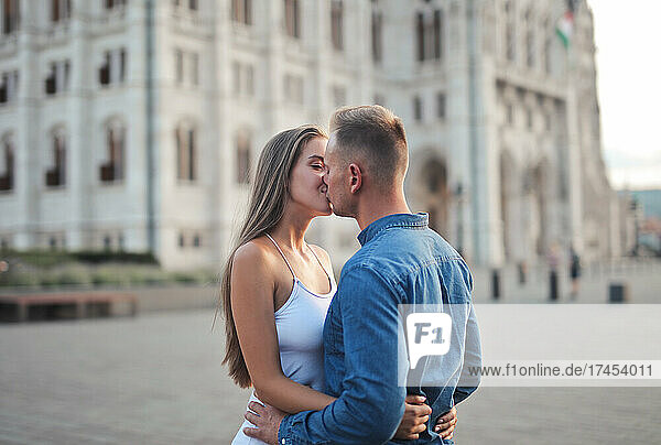 young couple is kissing in the background of the parliament in b