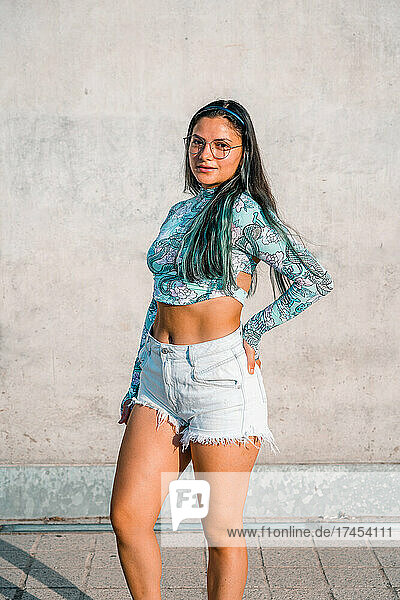 Latin brunette girl posing in front of a wall