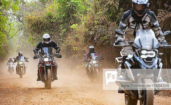 Group of men riding their adventure motorbike on dirt road in Cambodia