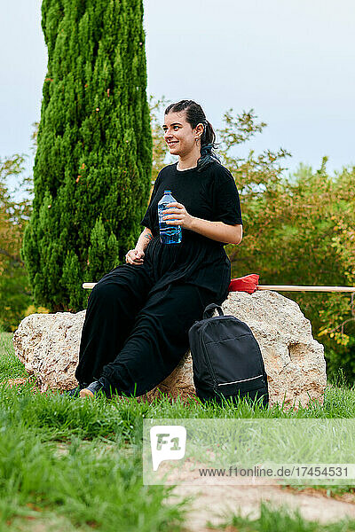 Woman holds a bottle of water after training in a park