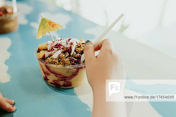 Child reaches for Acai and pineapple granola bowl