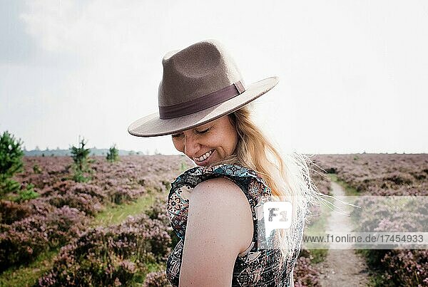 portrait of woman with hat on shyly smiling whilst outside in summer