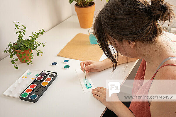 woman painting with watercolors in her studio at home