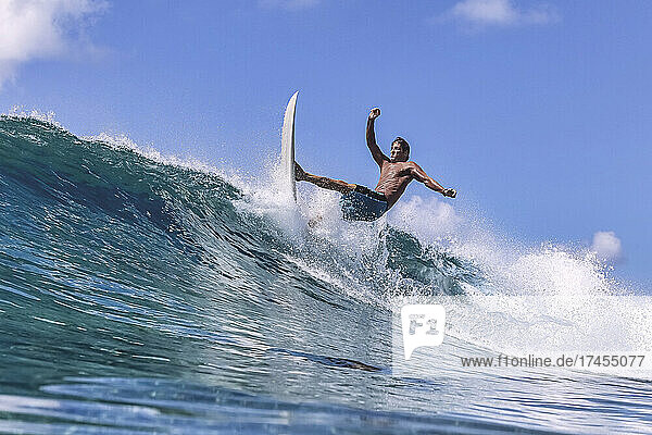 Man with surfboard surfing on sea wave against clear sky