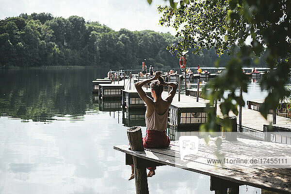 Person sitting on wooden jetty overlooking beautiful lake in Poland