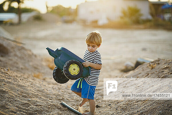 Young boy playing with toy trucks in the desert