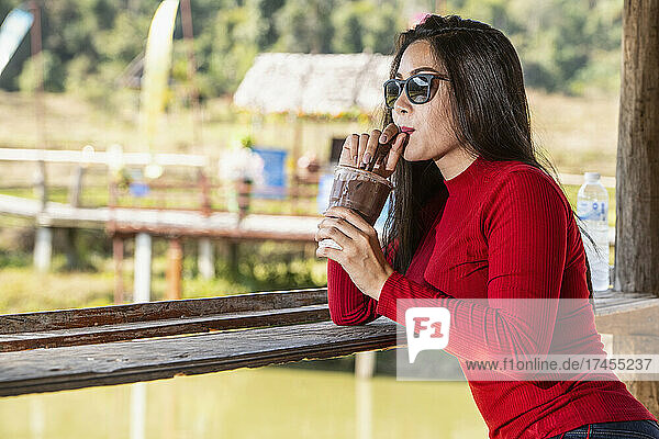 Thai woman enjoying iced beverage at outdoor cafe in north Thailand