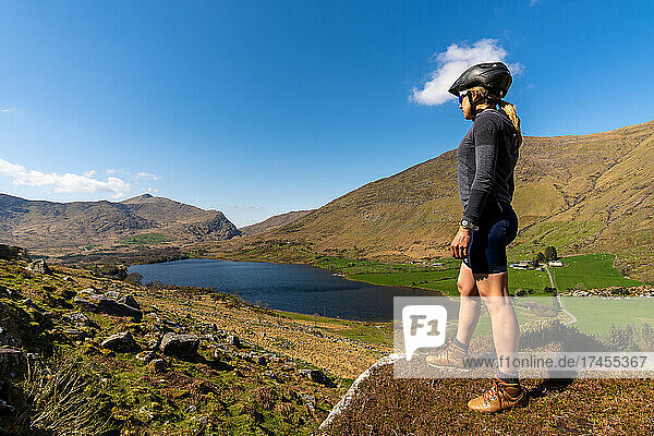 Female cyclist admiring mountainous scenery at Gap of Dunloe Kerry mou