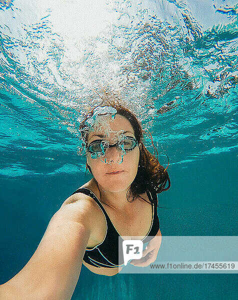 Underwater image of woman blowing swimming in a pool.