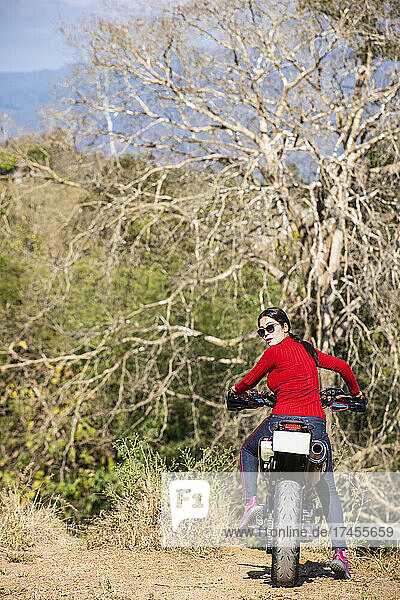woman riding her motorcycle on dirt road in north Thailand