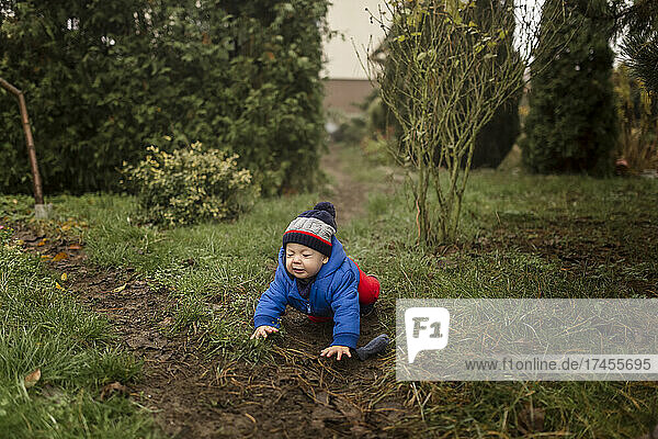 Toddler boy falling down on wild path in garden