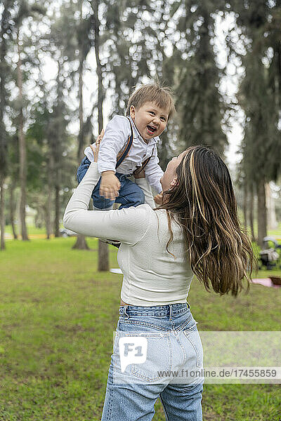 Mother raising her child while they laugh happily outdoors