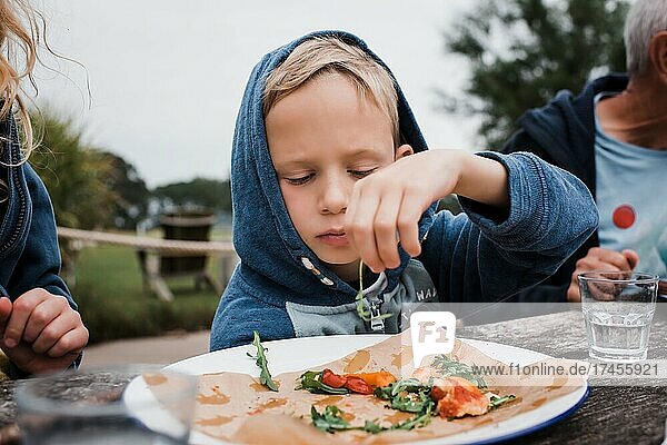 boy eating pizza outdoors with his family in the garden